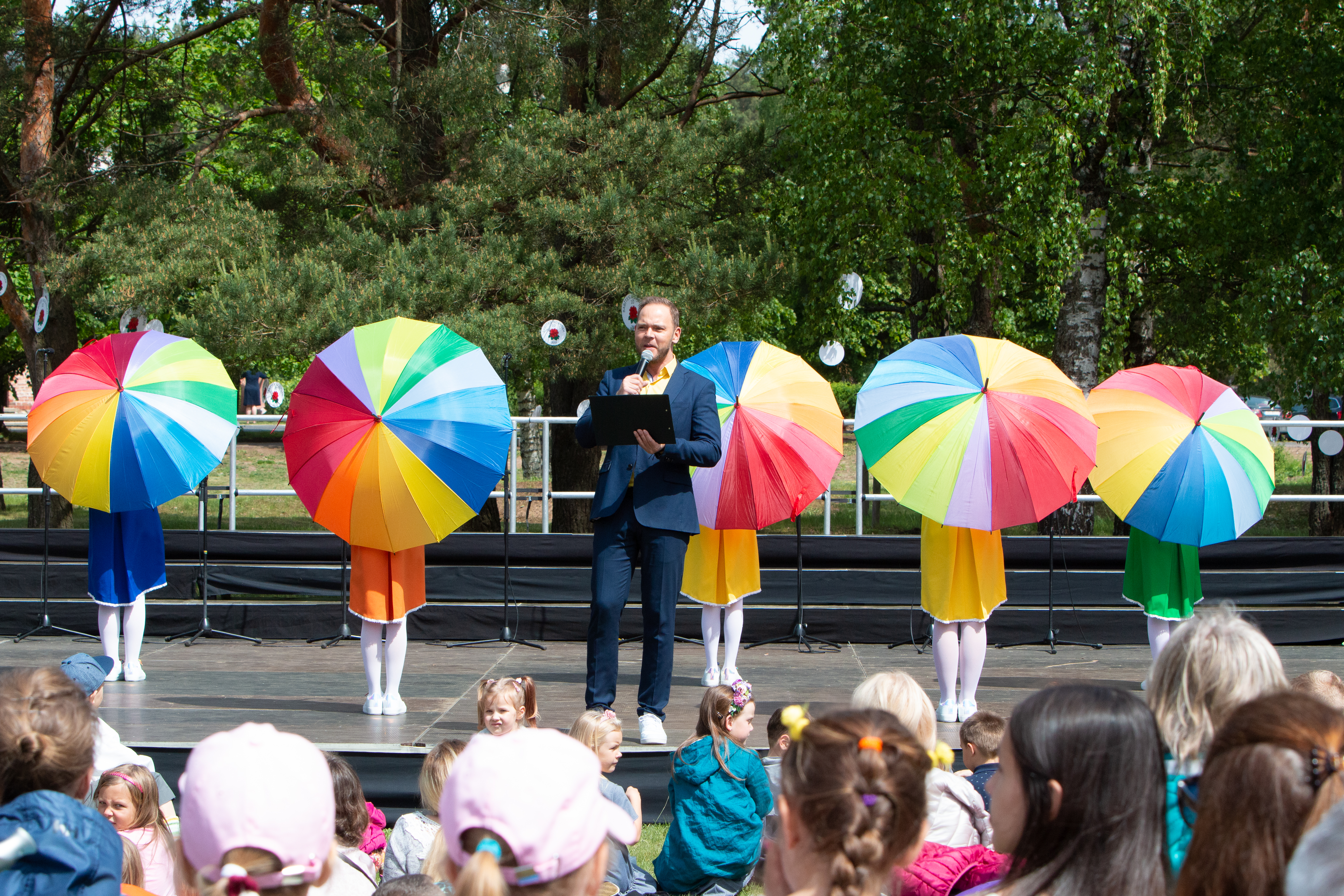 Bērnu kolektīvs ar krāsainie lietussargiem uzstājas pasākumā