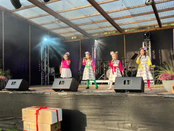 popgrupas mazās dalībnieces krāsainos tērpos uz skatuves