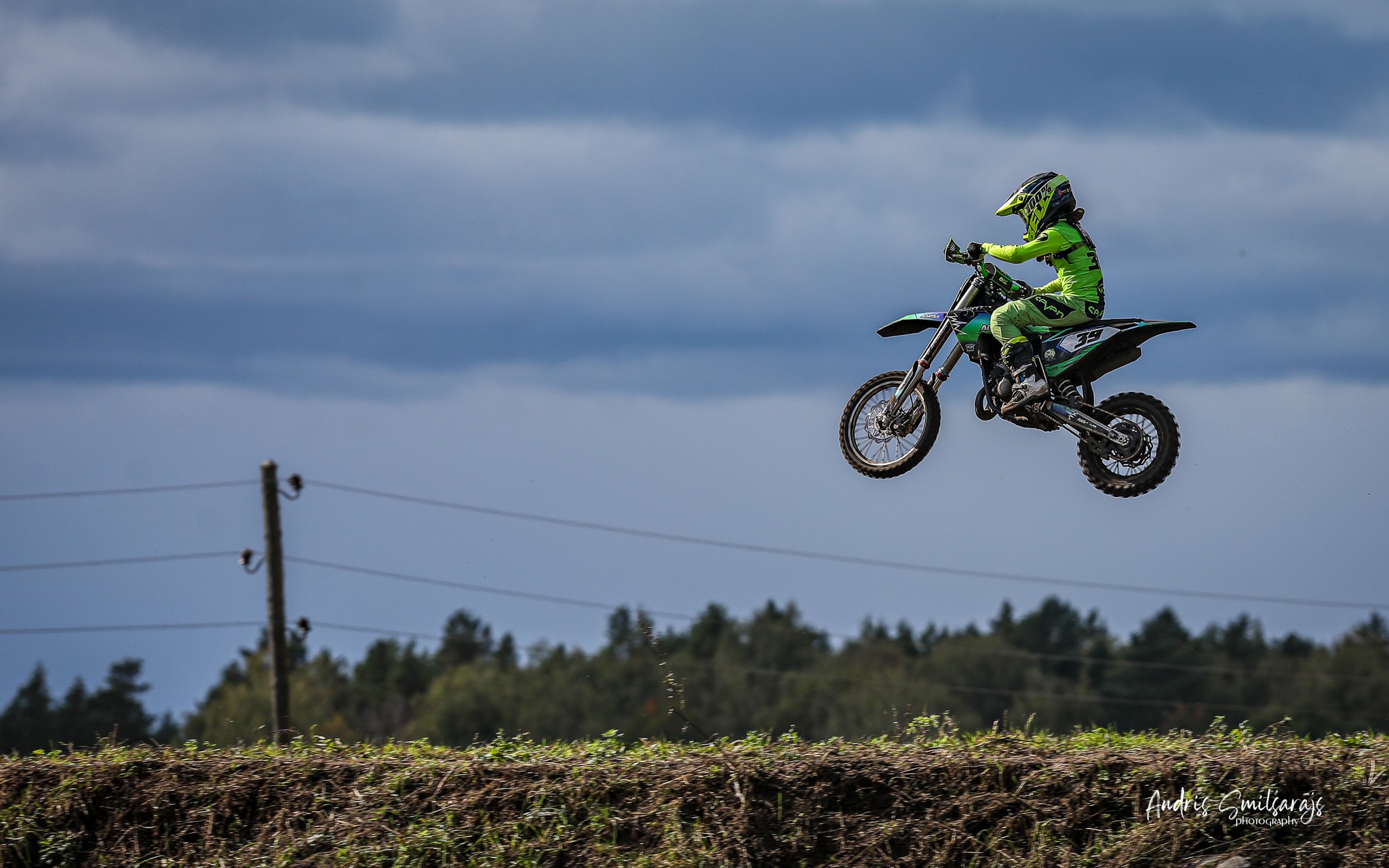 Motokrosa braucējs palēcies gaisā virs dubļainas trases