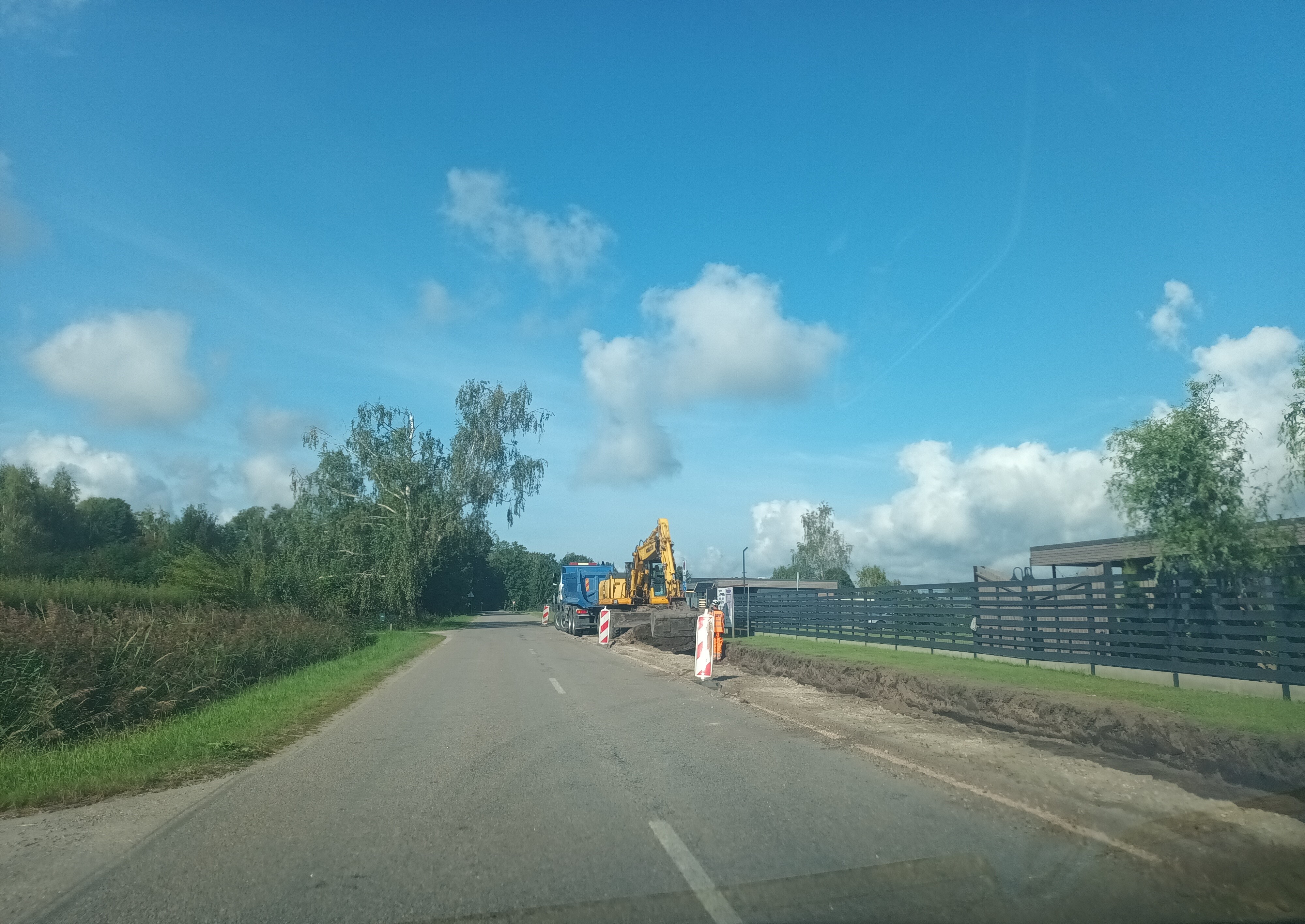 Asfaltēta ceļa posms remontdarbu laikā saulainā vasaras dienā