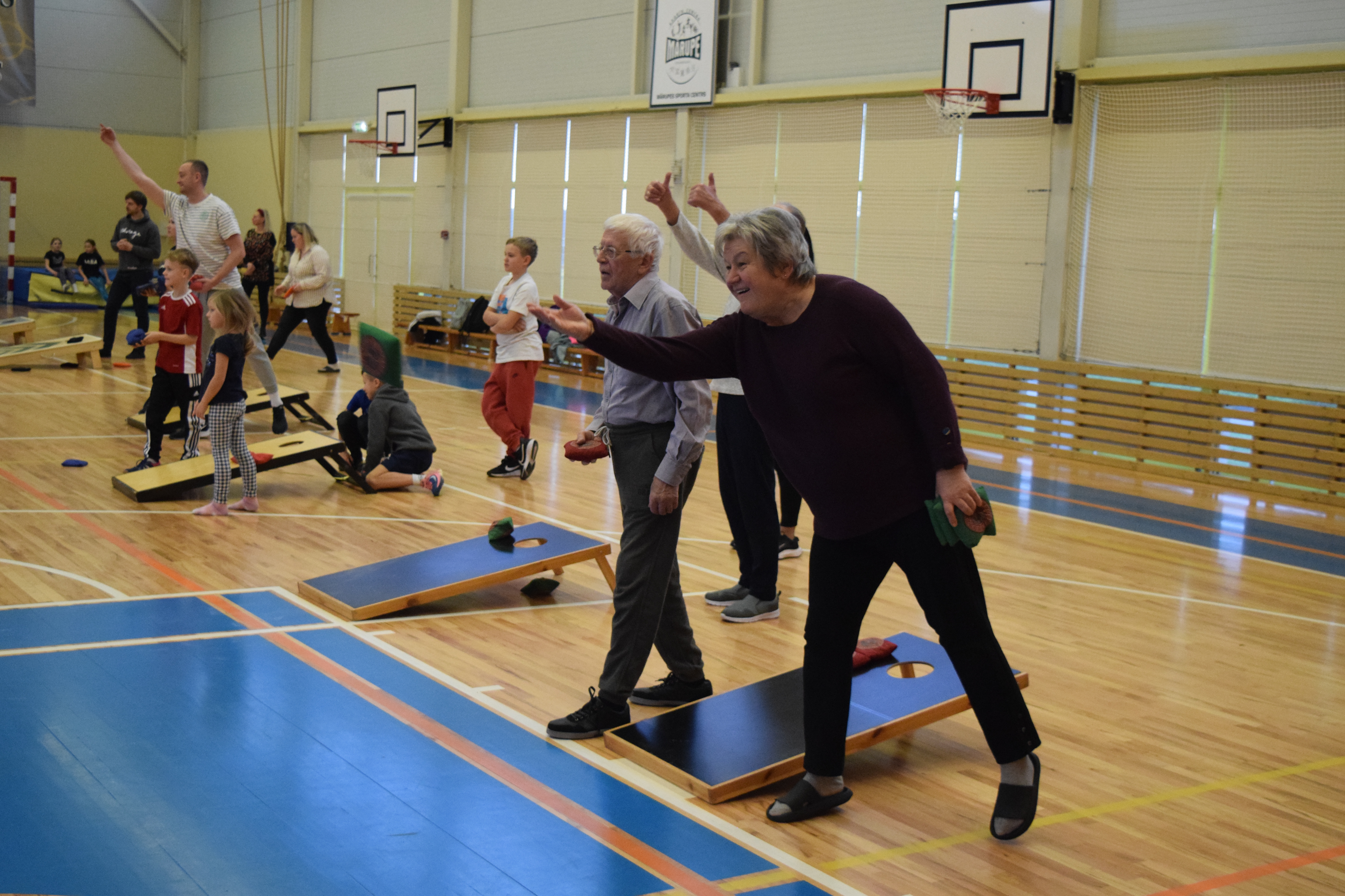 Seniori bmet auduma maisiņu uz koka platformas sporta zālē