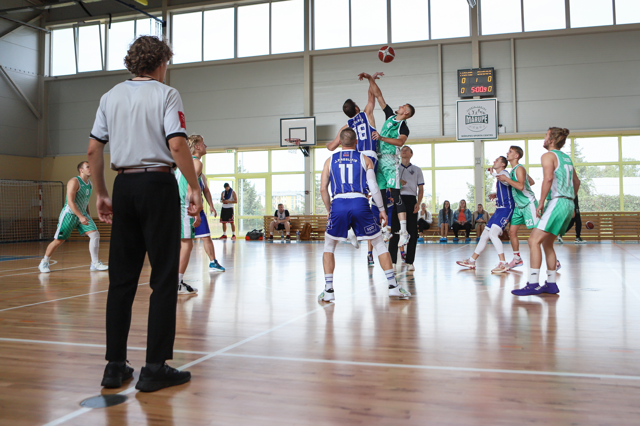 Spēles tiesnesis noraugās uz cīņu par bumbu basketbola laukumā