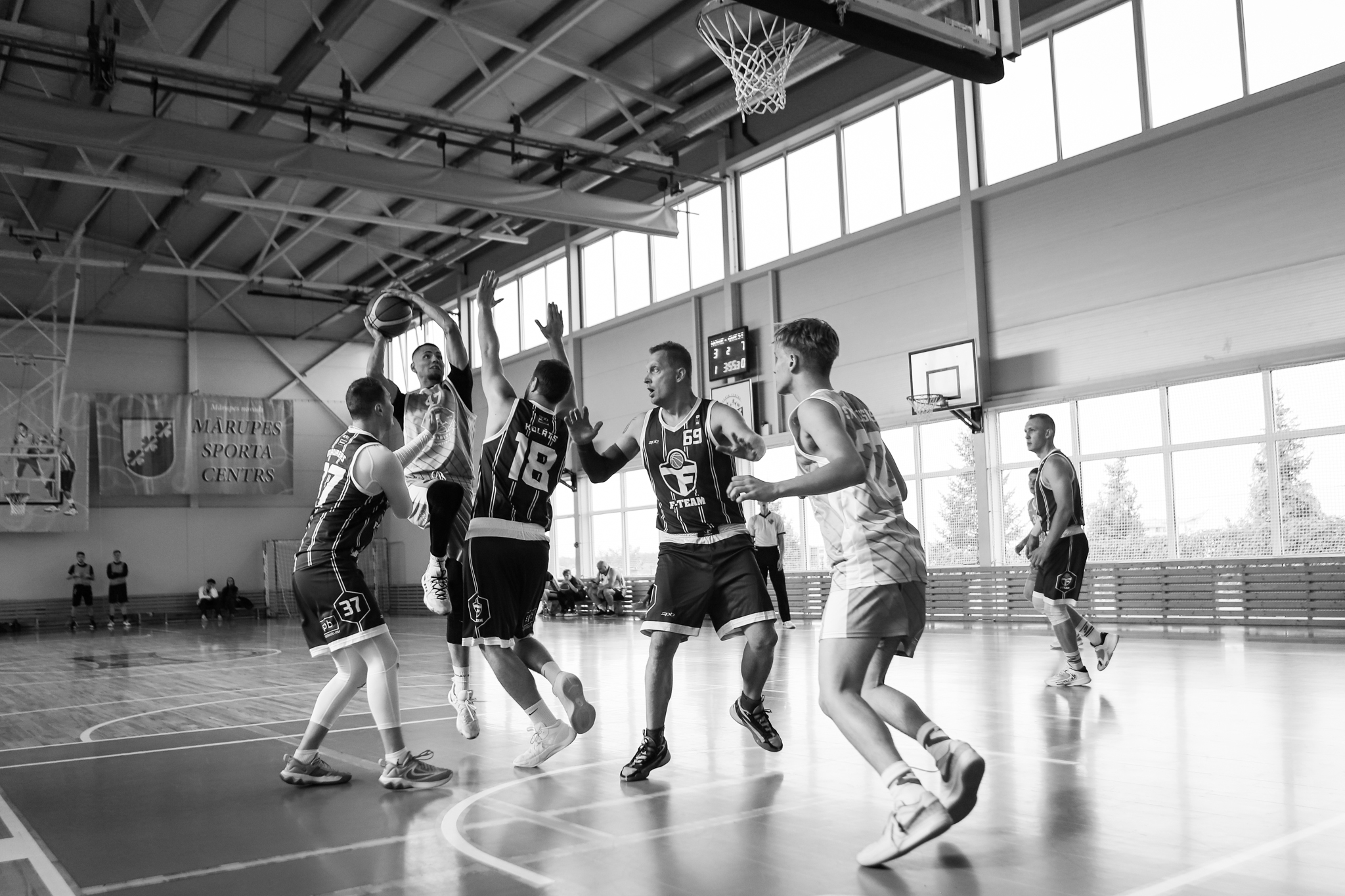 Basketbolisti cīnās par bumbu basketbola laukumā