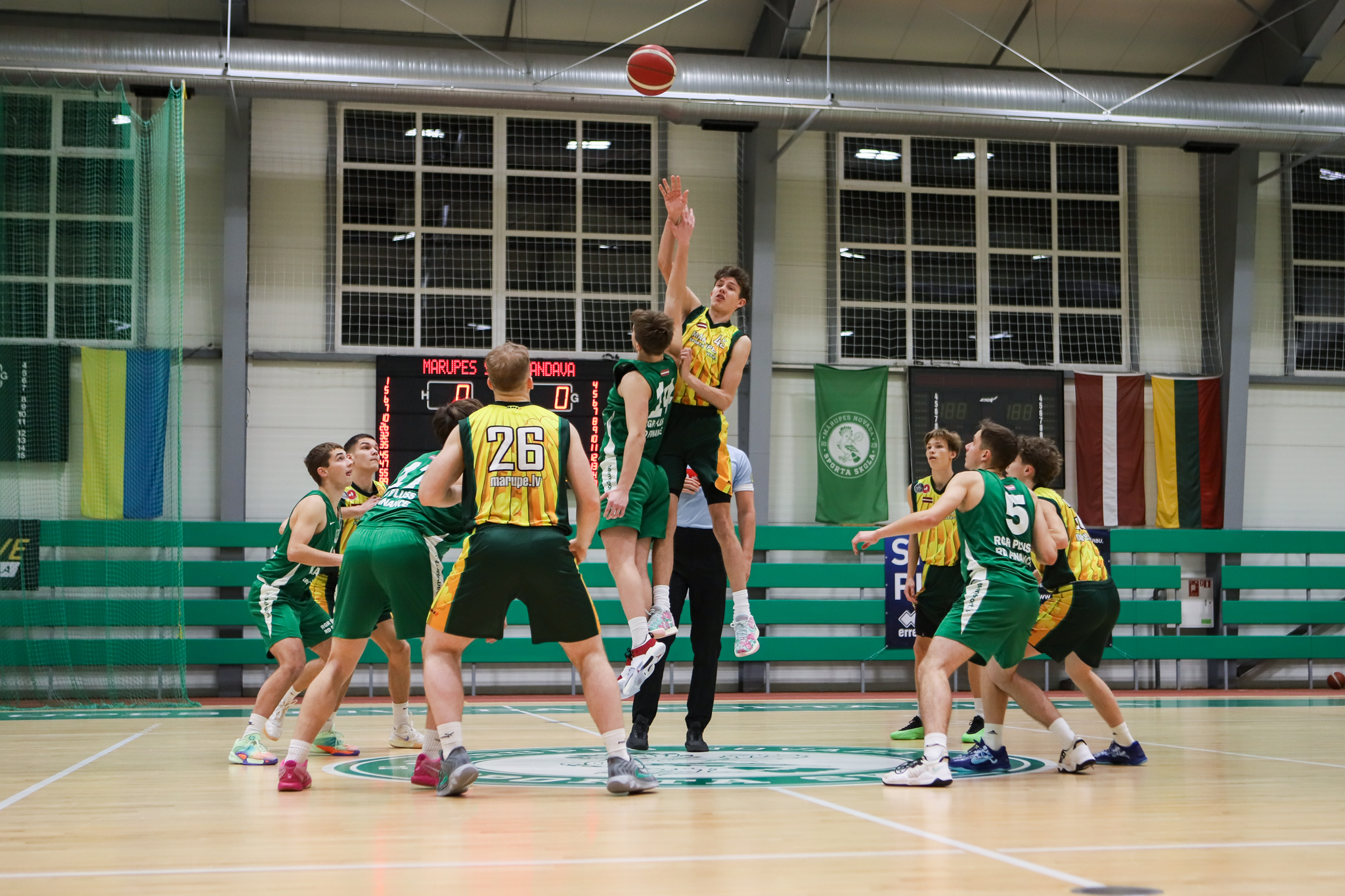 Basketbolisti spēlē sporta zālē