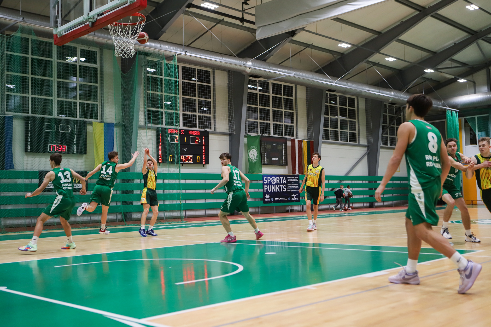 Basketbolisti spēlē sporta zālē