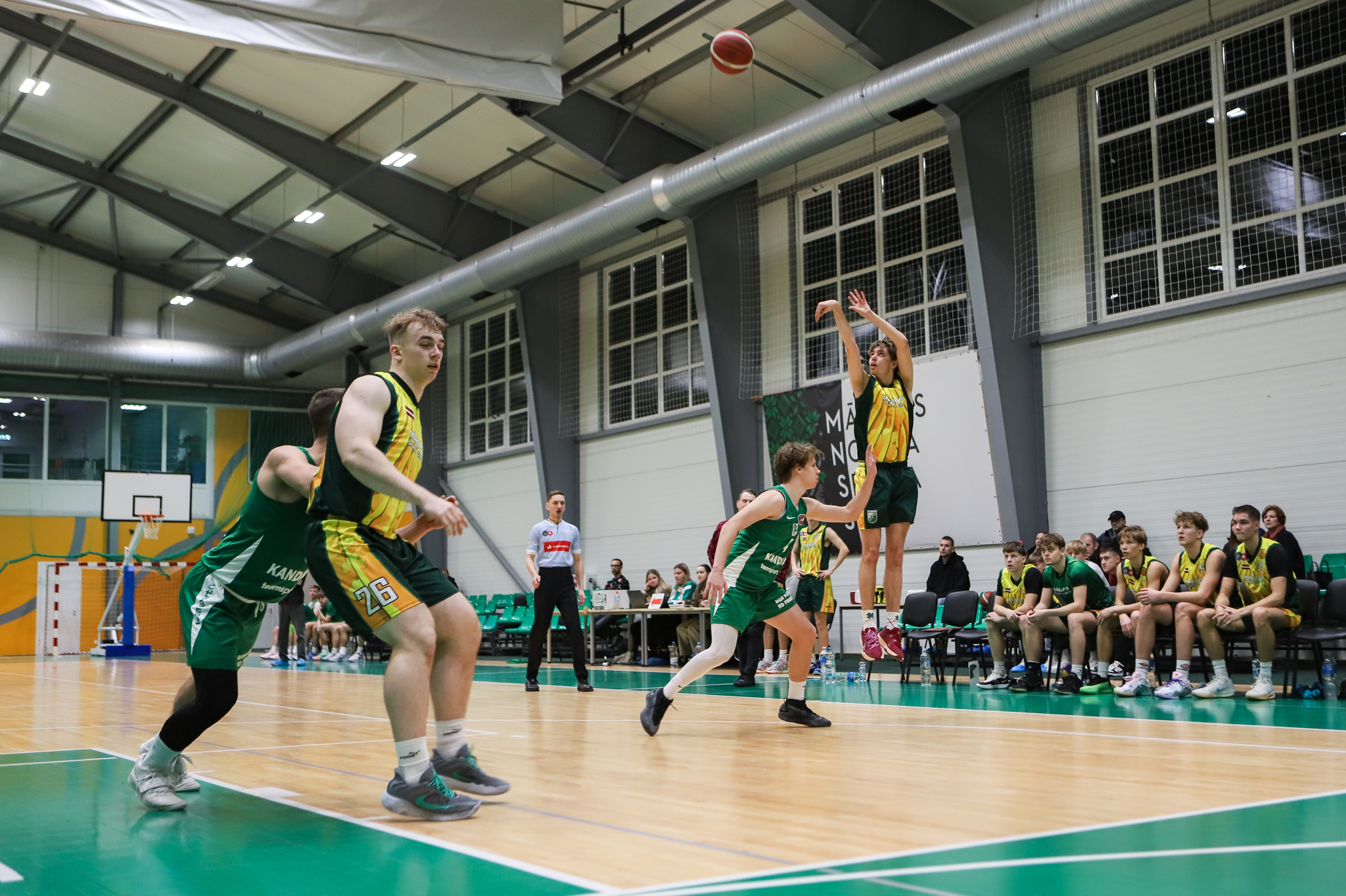 Basketbolisti spēlē sporta zālē