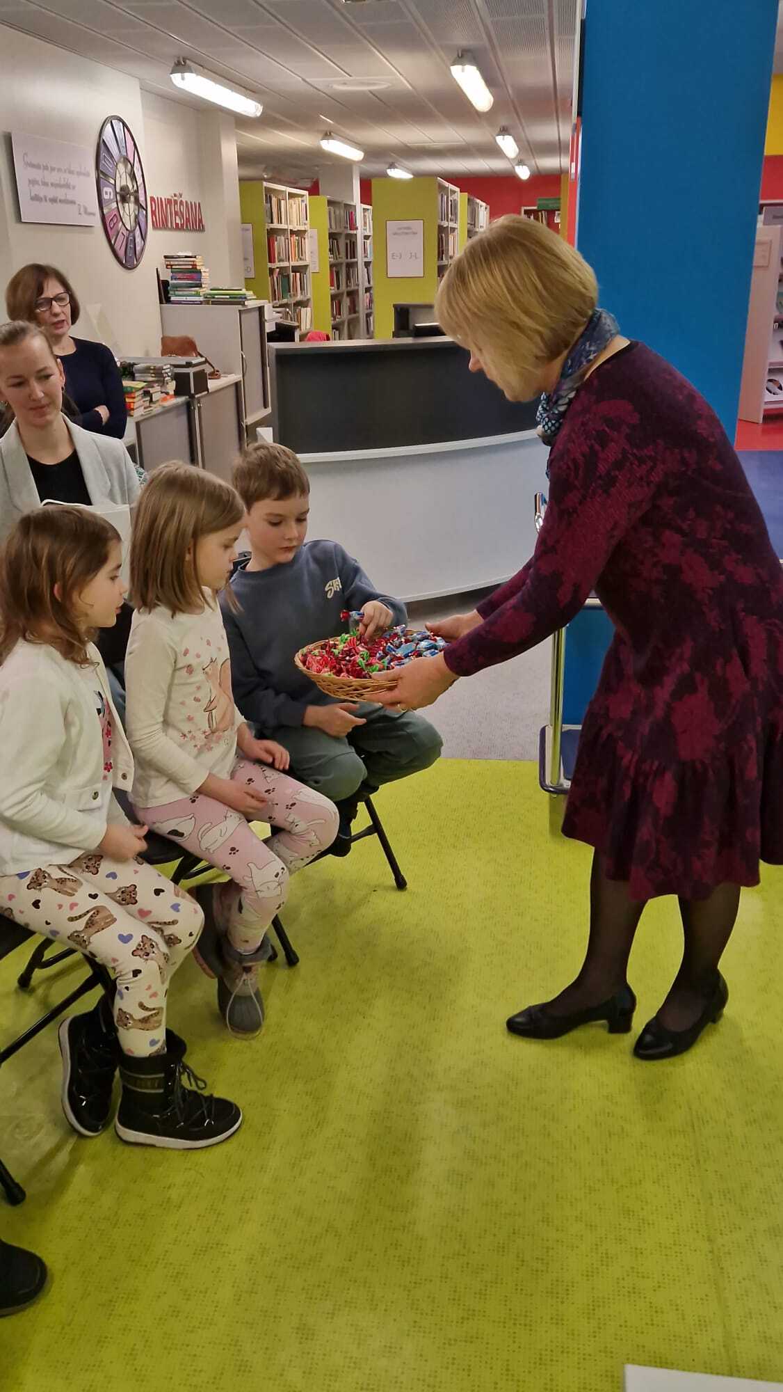 Bērni saņem konfektes bibliotēkas pasākumā par grāmatu lasīšanu