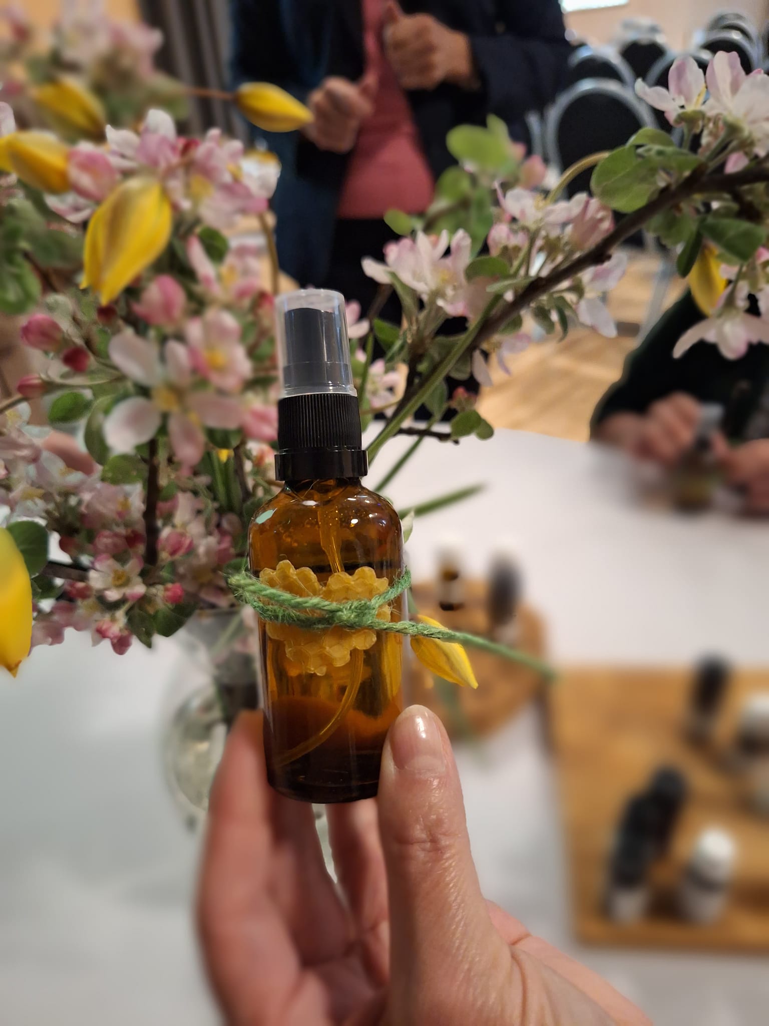 Smaržu eļļas pudelīte radošajā darbnīcā uz ziedu fona