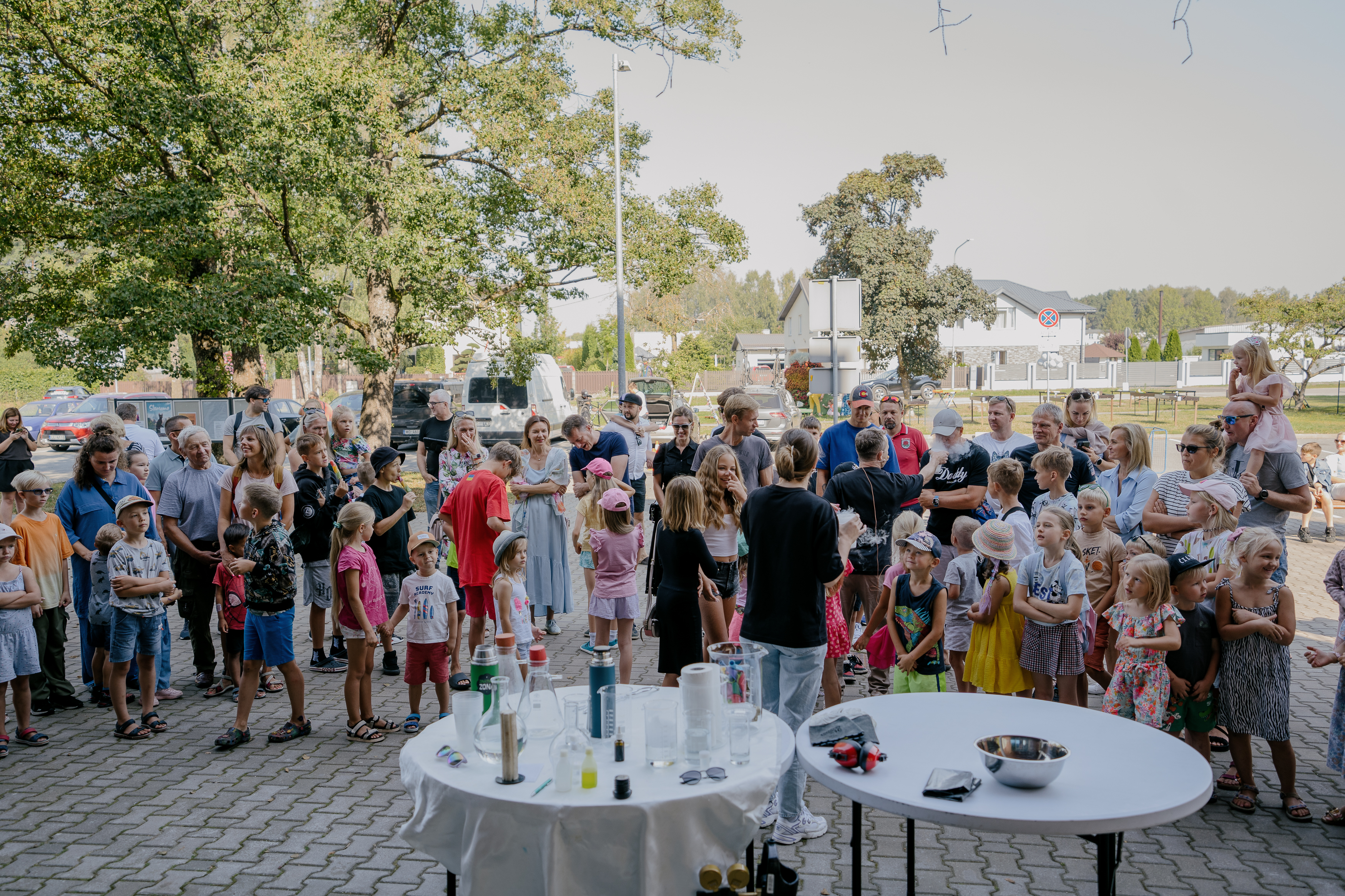 Bērnu pūlis brīvdabas pasākumā pie zinātnes eksperimentiem