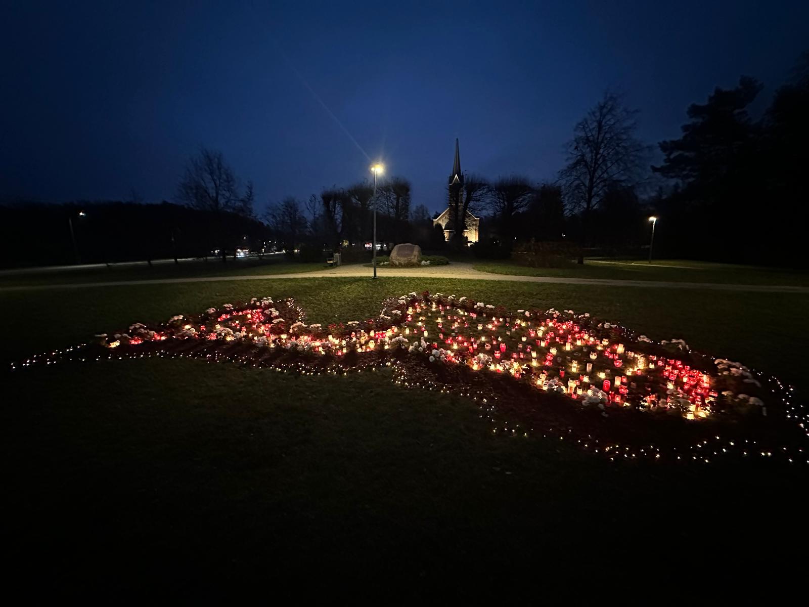 Vakara tumsā pļavā izgaismota Latvijas kontūra ar svecītēm