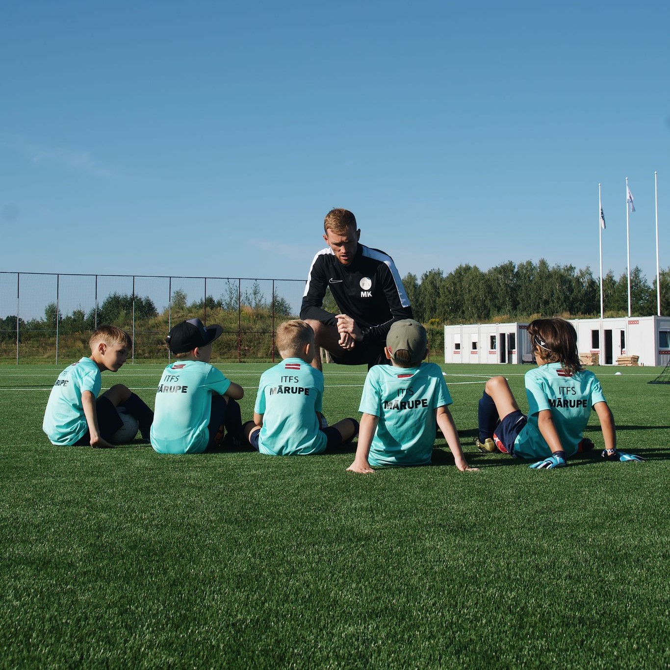 Mazi bērni zilos kreklos futbola laukumā