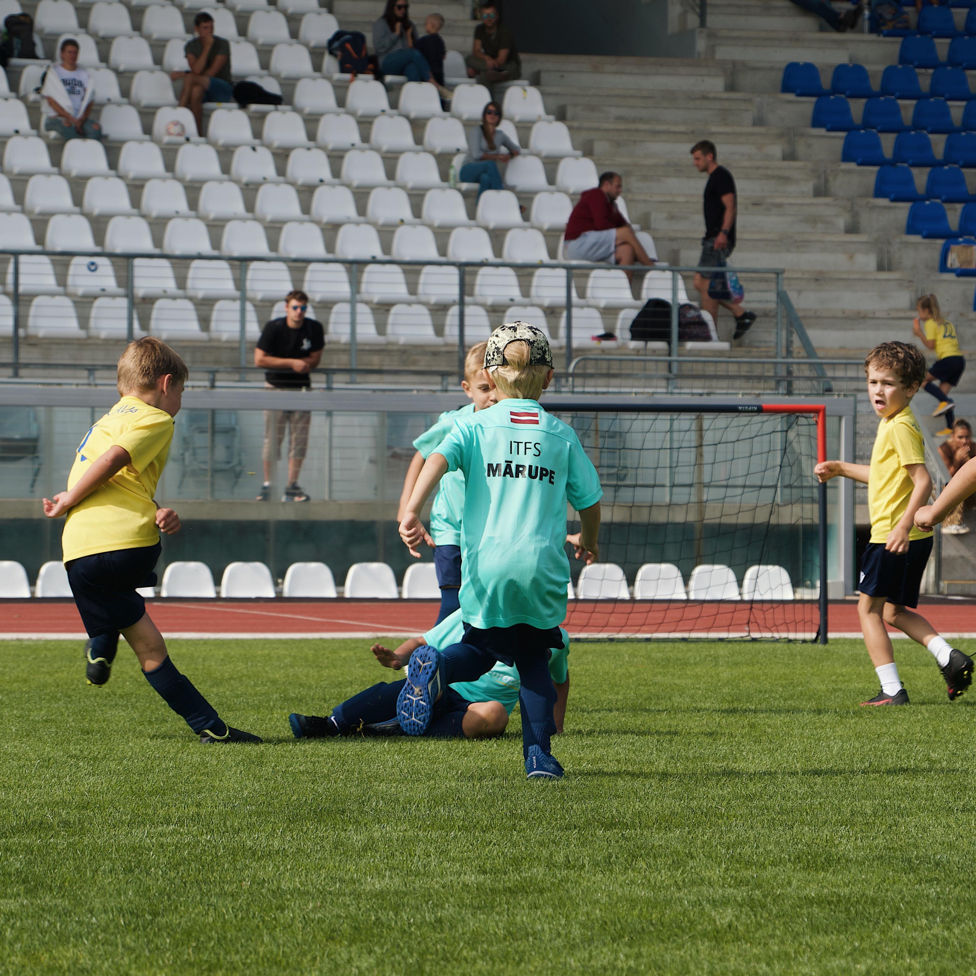 Mazi bērni zilos kreklos futbola laukumā