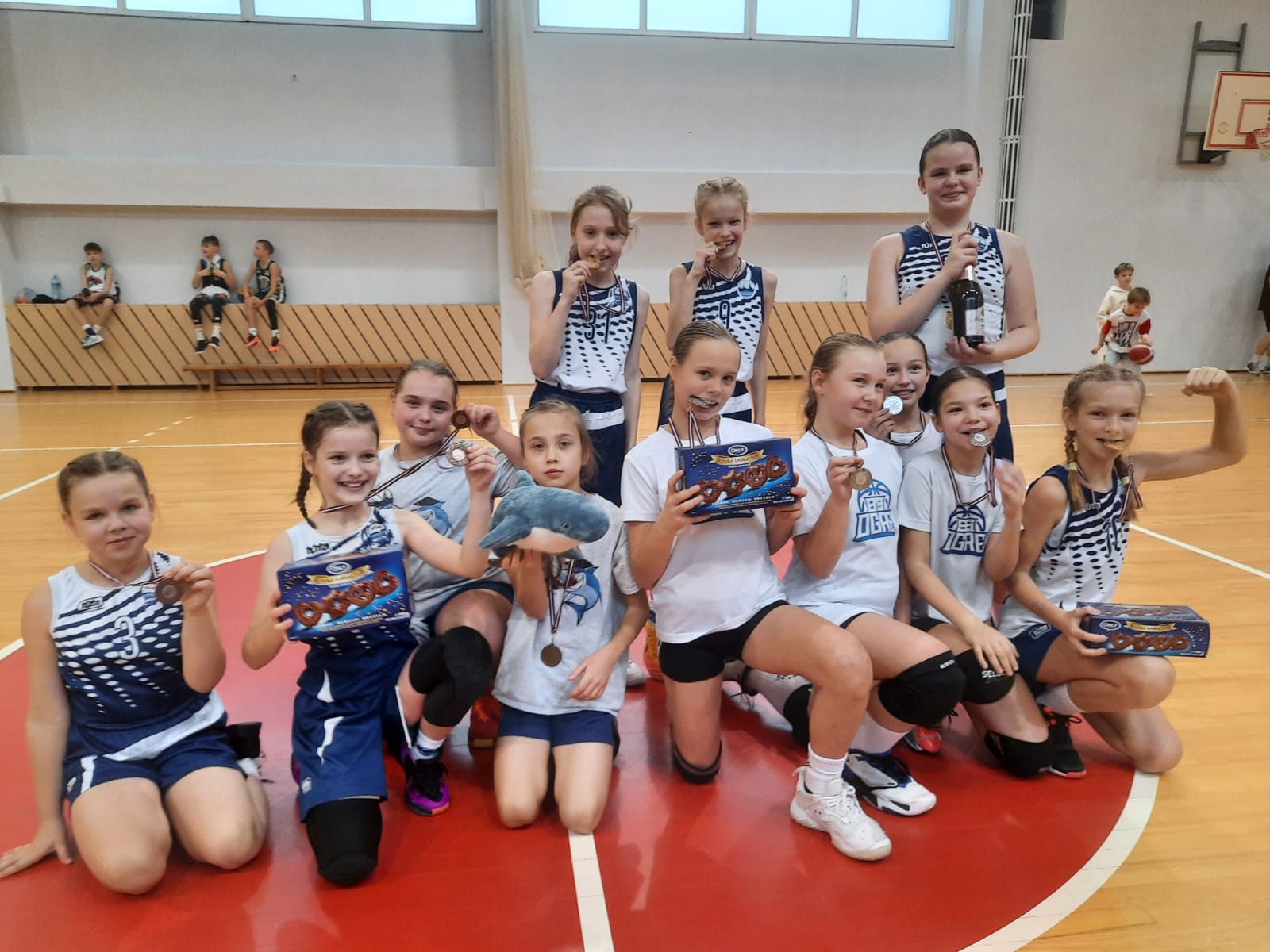 Basketbolisti stāv rindā sporta zālē