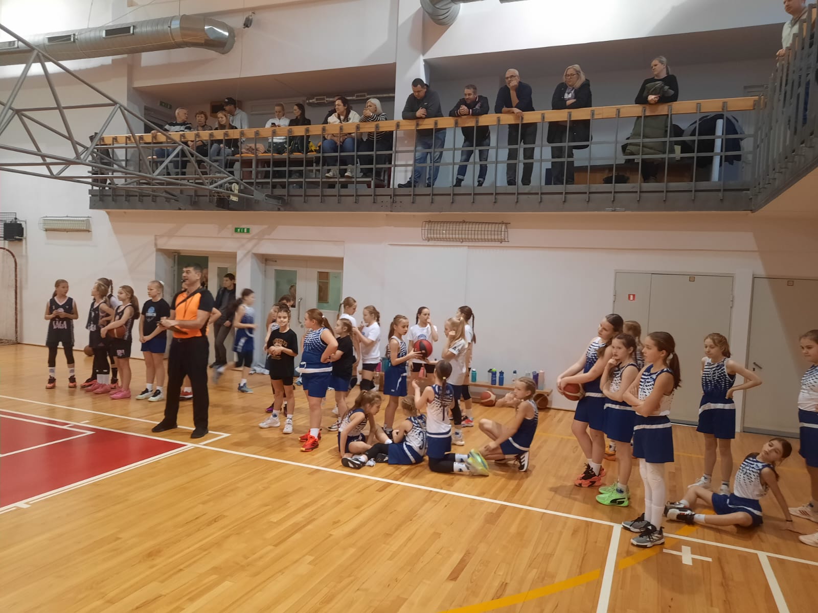 Basketbolisti stāv rindā sporta zālē