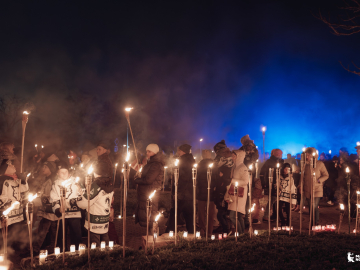 Cilvēki ar lāpām rokās dodās lāpu gājienā tumšā vakarā