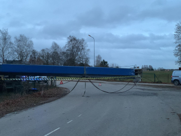 Ceļa krustojums un zils ceļamkrāns pāri tam drūmā rudens vakarā