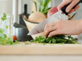 Sievietes rokā virtuves nazis ar kuru tiek kaplēta rukola