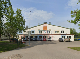 Mārupes novada Sporta skolas ēka - balta ar krāsainiem elementiem uz sienas apdares. Pie ēkas novietotas vairākas automašīnas.