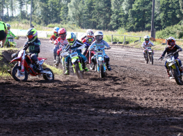 Motokrosa braucēji brauc ar motocikliem pa dubļainu trasi