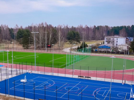 Sporta stadions ar zaļu futbola laukumu un zilu basketbola laukuma segumu