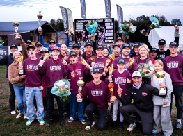 Vairāki motokrosa braucēji sarkanos džemperos ar kausiem rokās