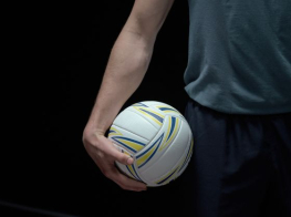 Vīrieša viena roka, kas tur plaukstā volejbola bumbu