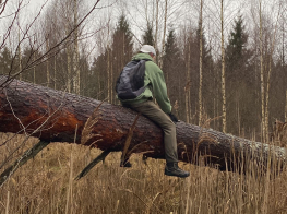 Jauniešu pārgājiens brīvdabā, cilvēks sēž uz koka stumbra