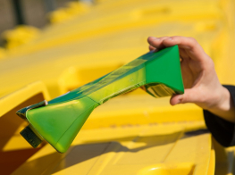 saplacināta dzērienu paka, kuru taisās izmest konteinerā