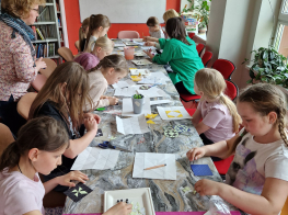 Radošā darbnīca - bērni sēž pie galda un veido savus darbiņus