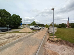 Ielu būvdarbi - ceļa posms ar laternu un mašīnu fonā