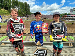 trīs puiši sporta tērpos stāv