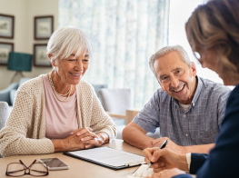 Senioru pāris pie galda runā ar sievieti