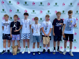 Puiši sporta tērpos stāv pie baltas foto sienas