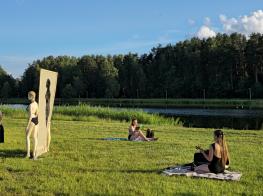 Sievietes performances laikā zaļā pļavā saulainā vasaras dienā pie dīķa